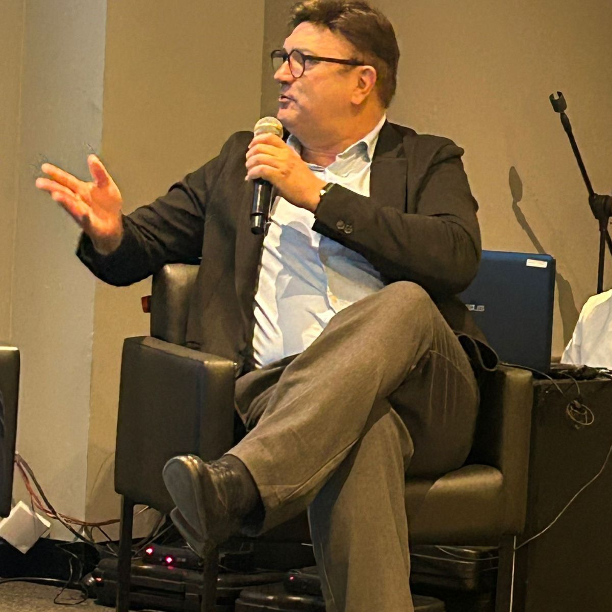 Palestrante em debate ativo, gesticulando durante painel no evento